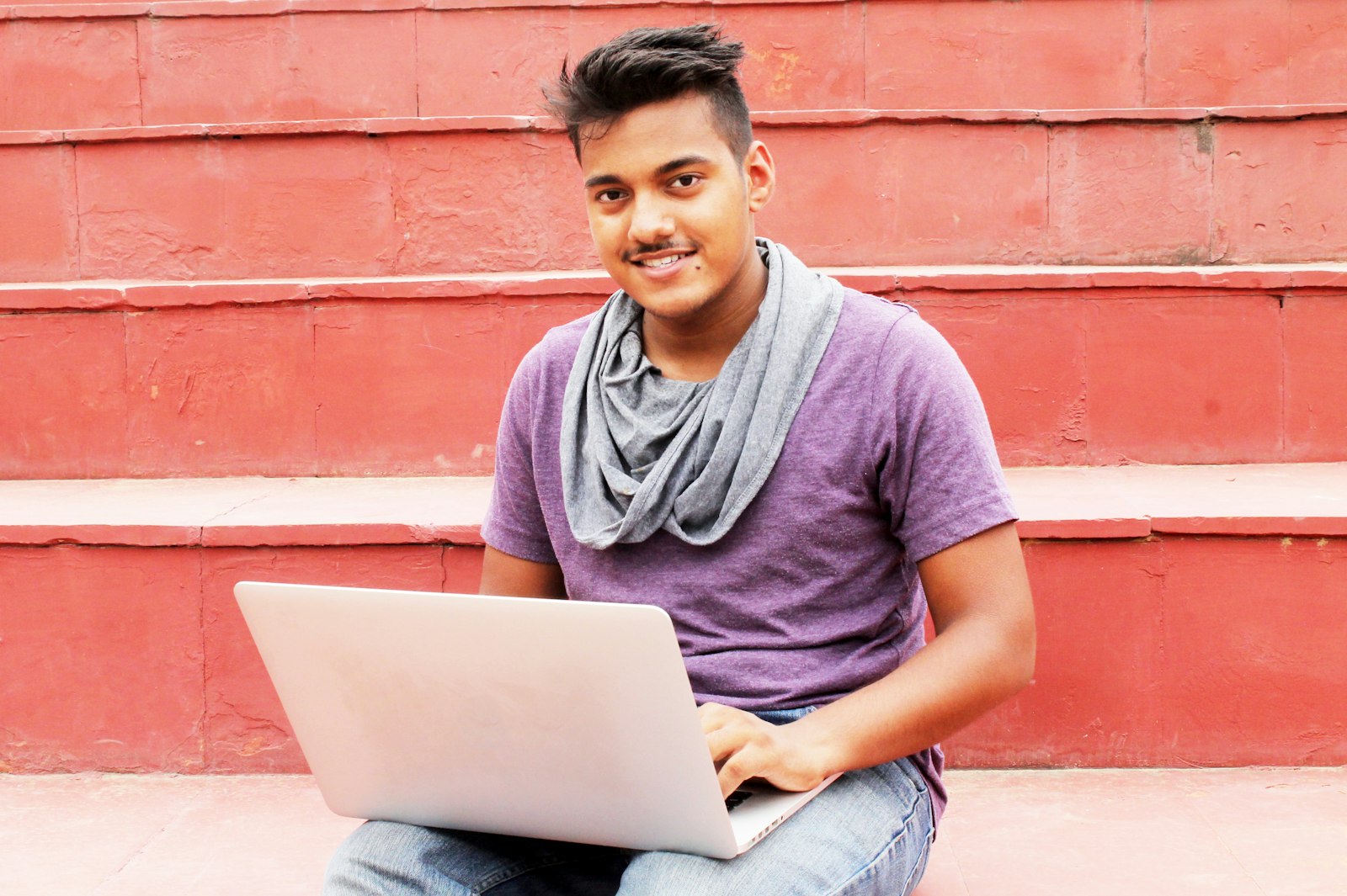 Young man with a laptop sitting on steps