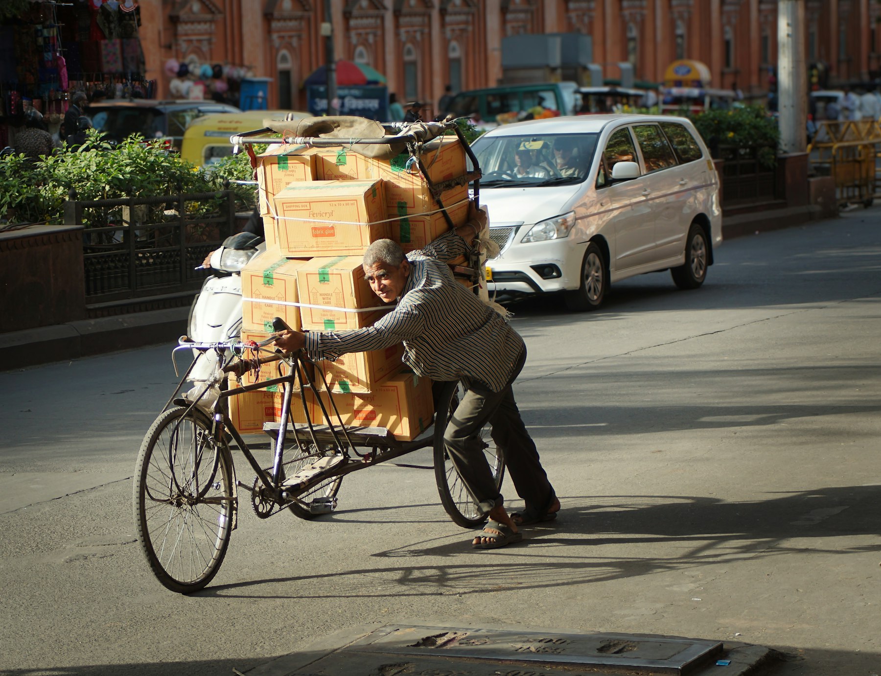 Delivery man pushing a bicycle loaded with boxes