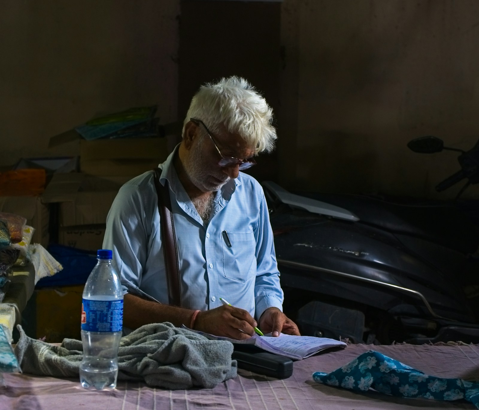 Cloth shop owner writing bills by hand in his book at the counter