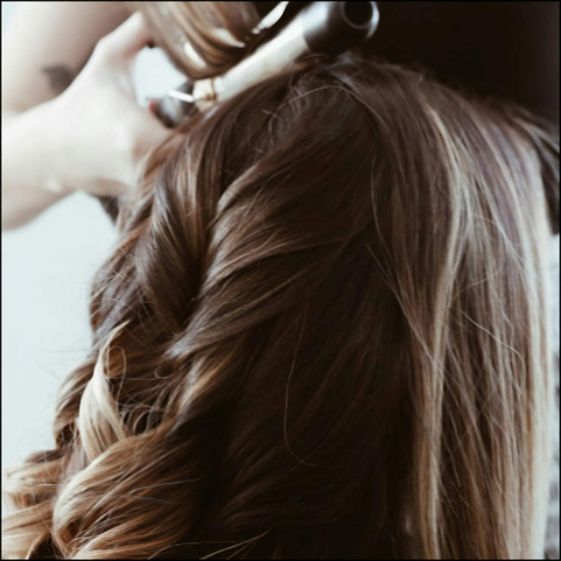 Hair stylist curling a customer's hair at a salon